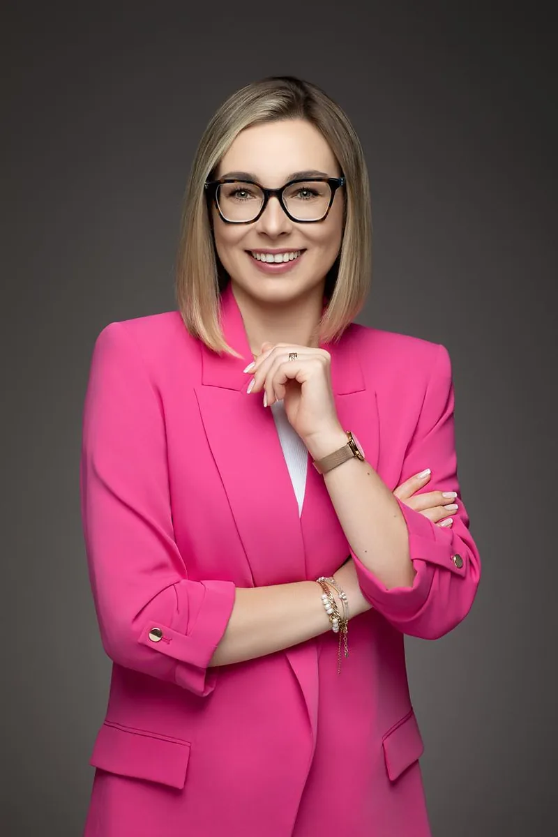 Justyna Krysiak w różowej marynarce, uśmiechnięta